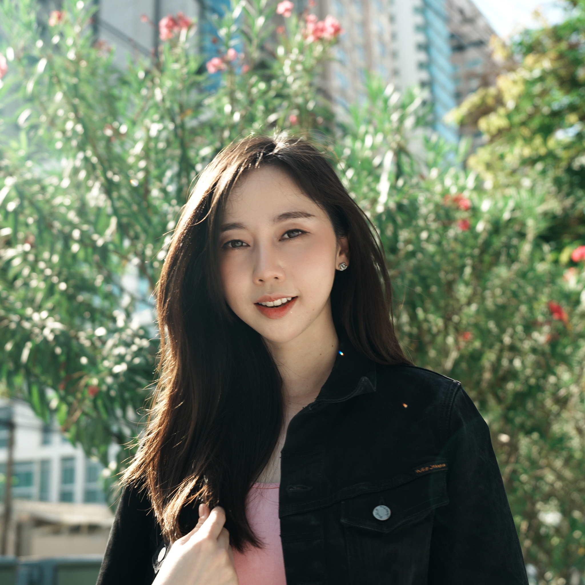 Medium close-up shot of girl smiling at the camera in front of a tree with flowers