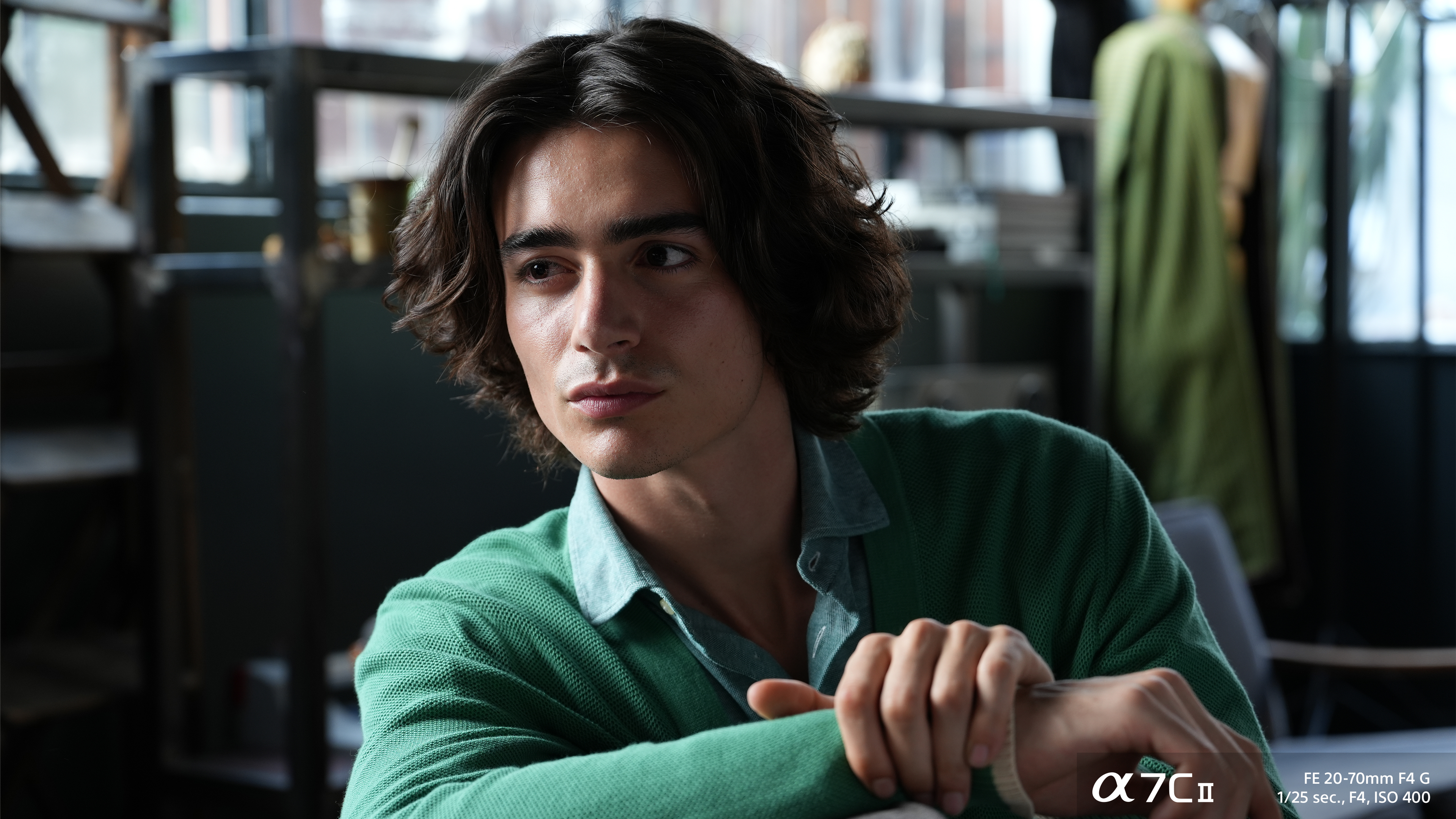 Close up of a young man in a green cardigan and shirt looking to the right