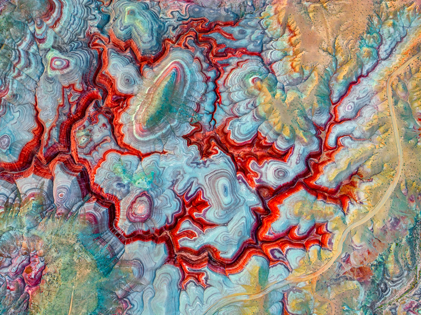 Aerial view of bright red ridges against a blue-yellow landscape