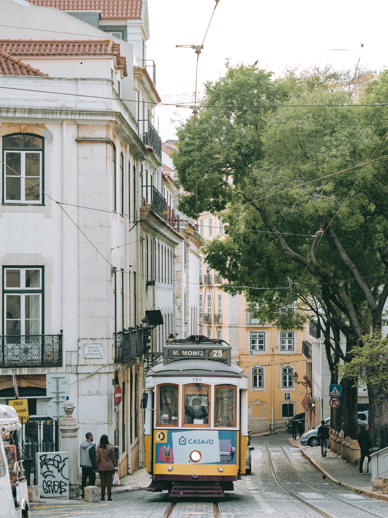 Street tram in Lisbon stopping by a building with a couple on the side