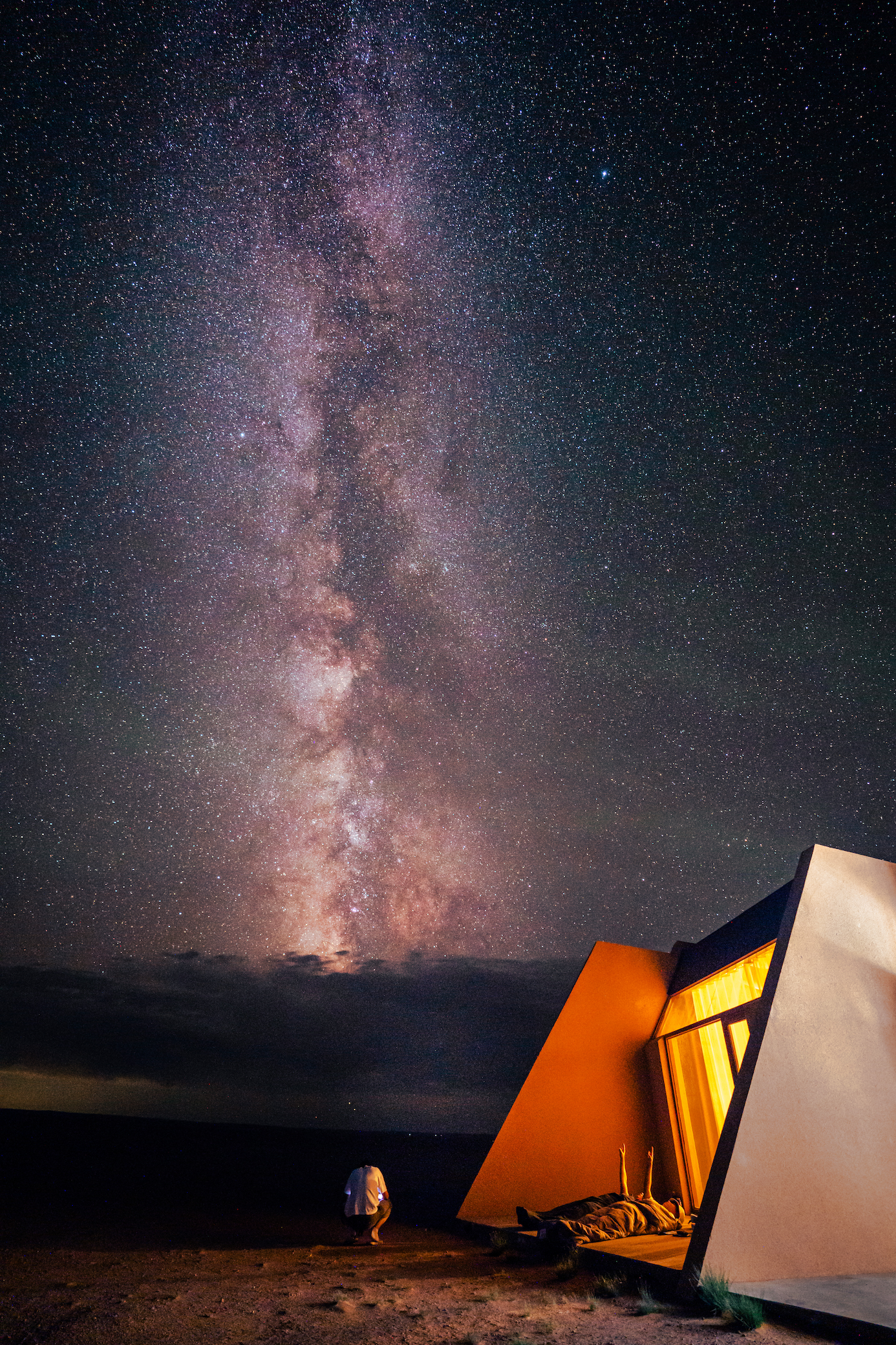 People lying down outside a lodge, looking up at the vast, starry sky