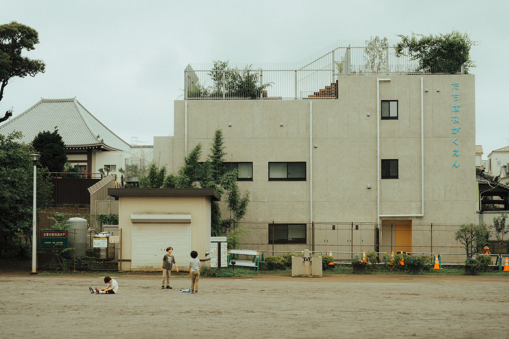 Three kids playing on a wide area in front of a multi-storey building