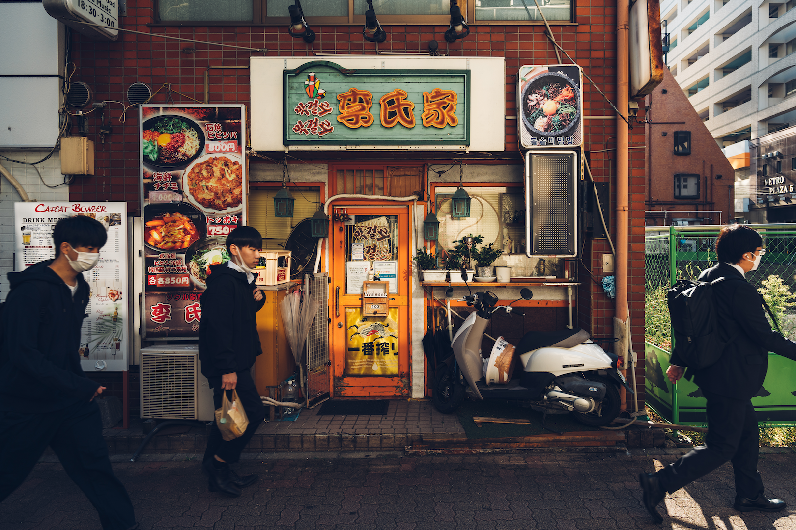 Exterior of a hole-in-the-wall Chinese restaurant, with people walking by