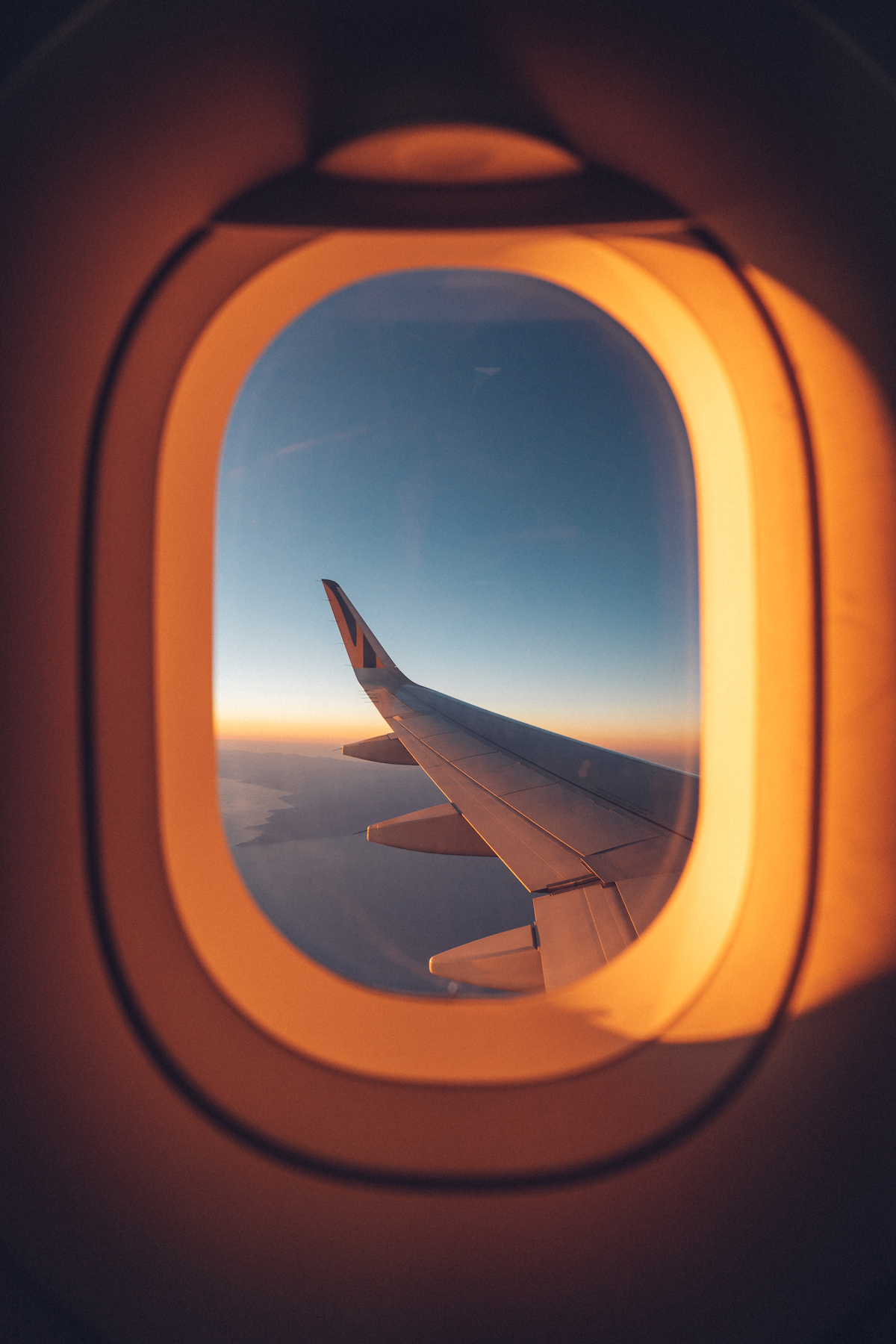 View of the plane wing over the ocean from a window seat with a glow