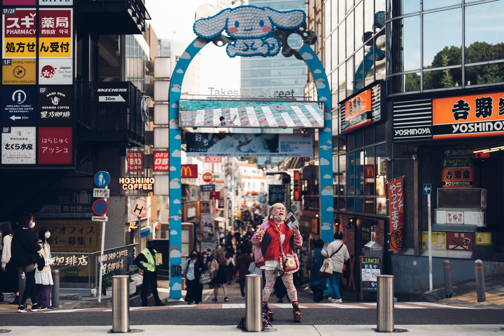 Woman in a colourful outfit standing at the entrance to Takeshita Street, Harajuku