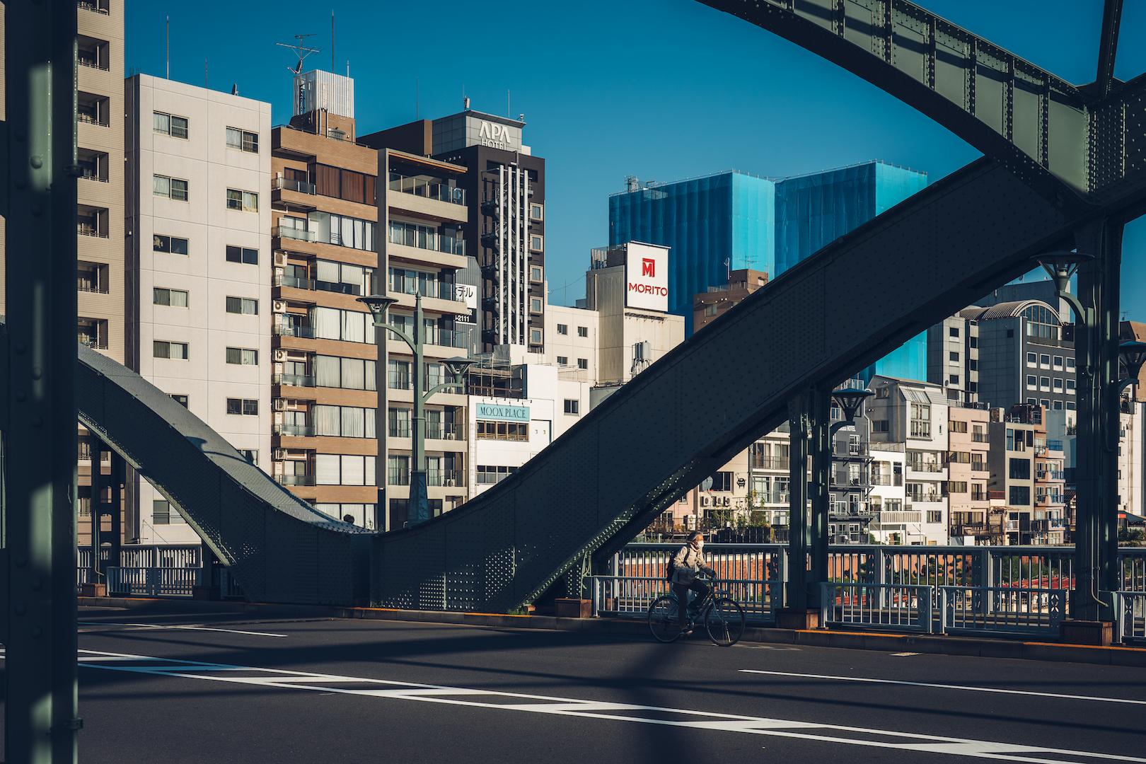 Elderly cycling across a bridge with buildings in the background