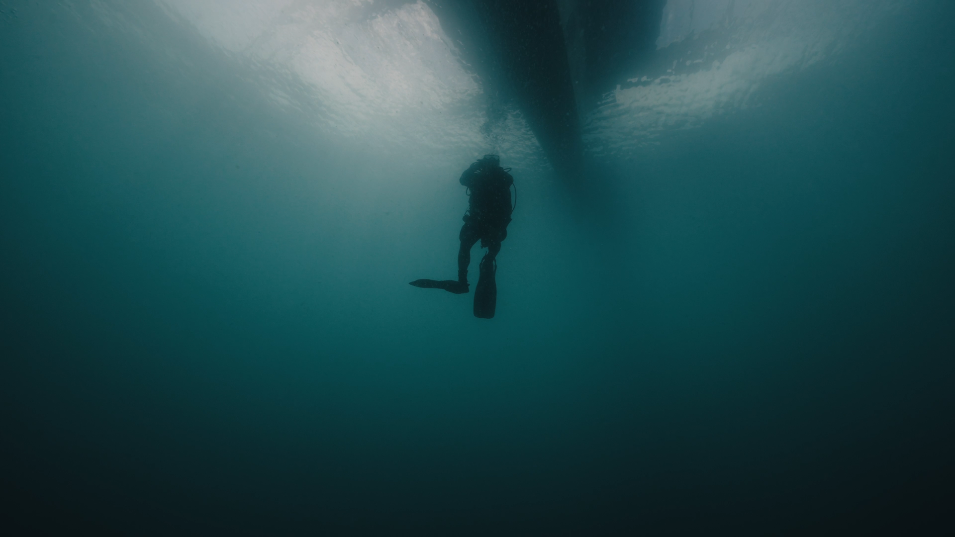 Silhouette of a diver swimming up, close to the diveboat 