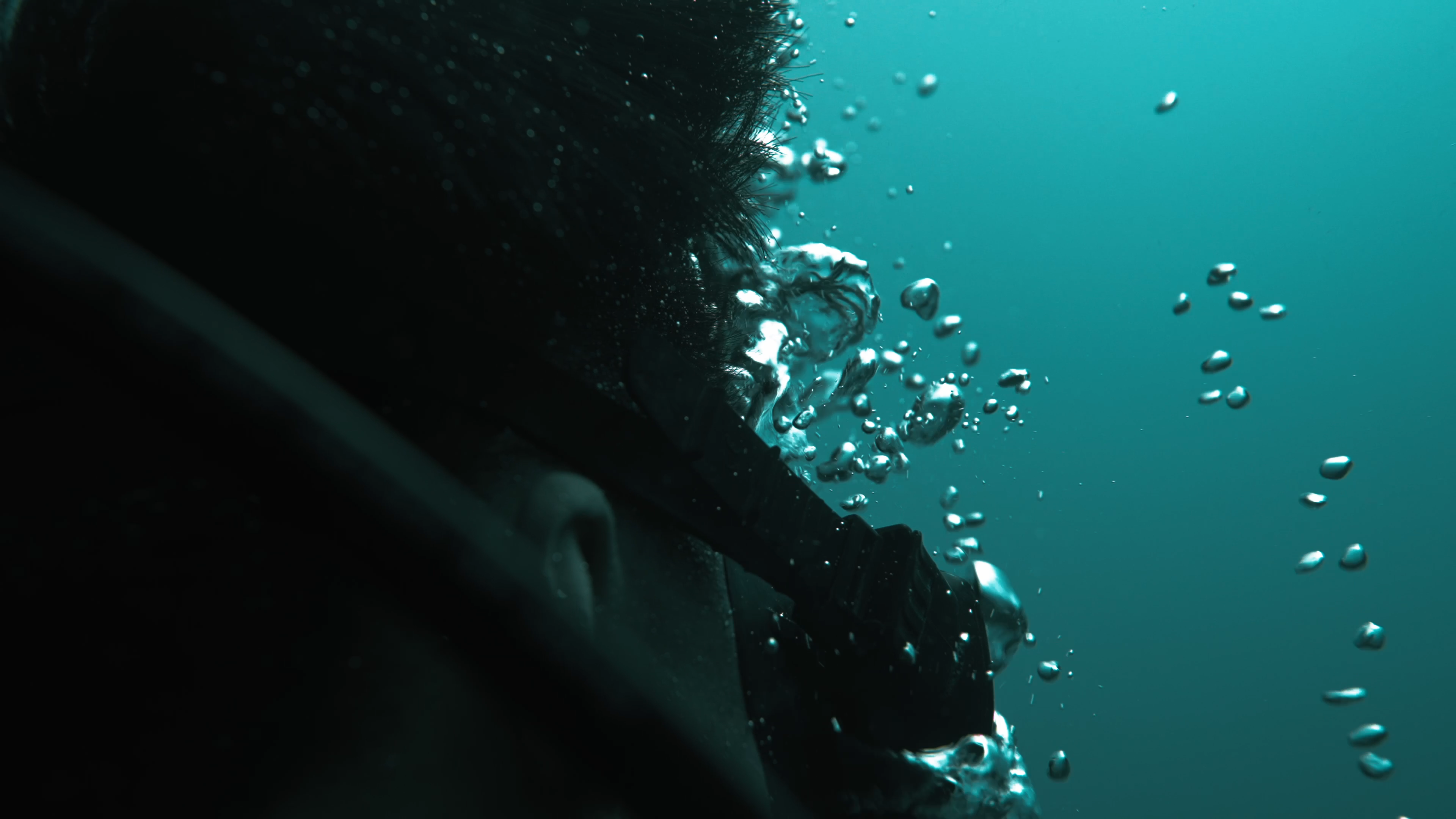 Close-up of the side profile of a diver, with air bubbles rising up